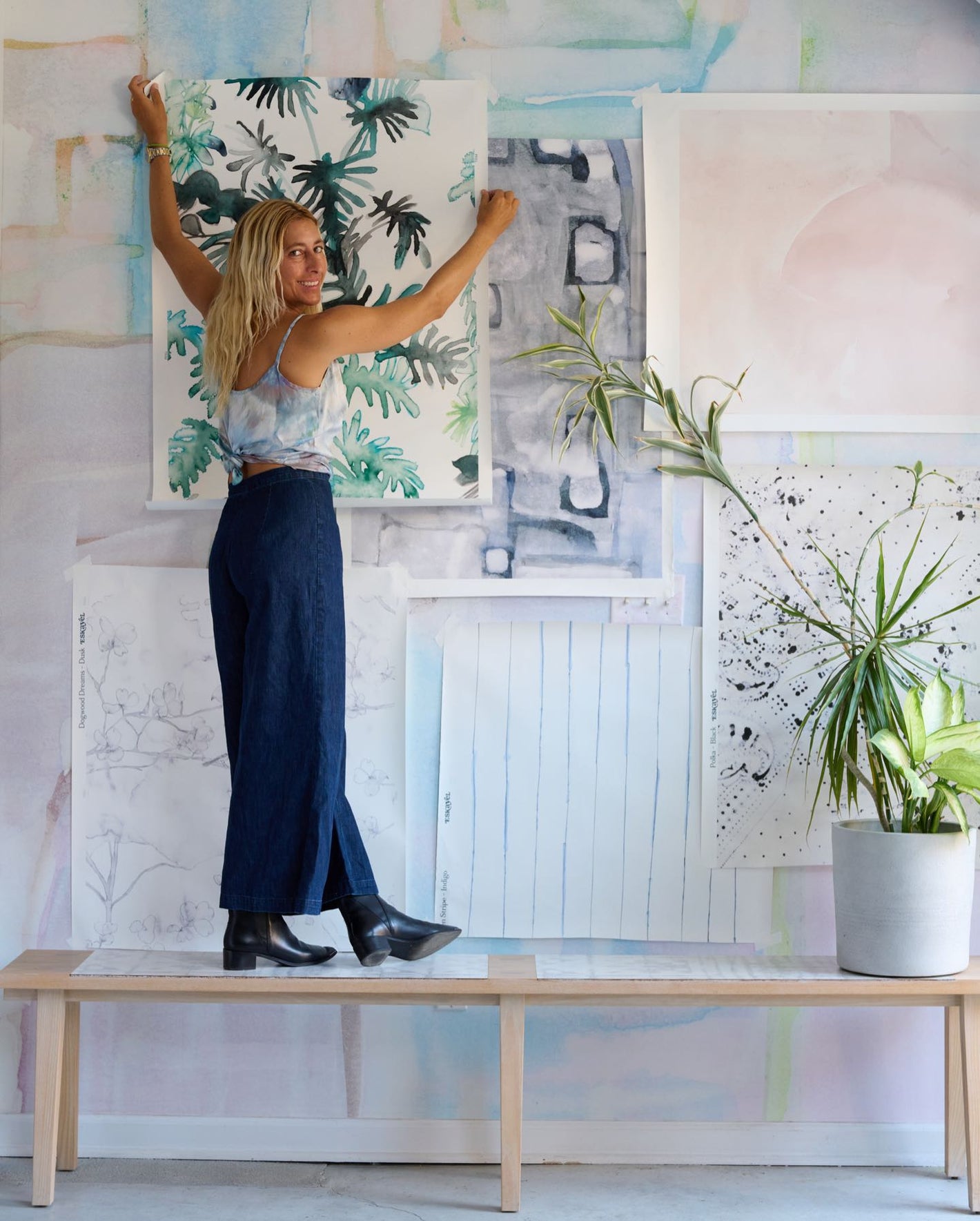 A woman standing in front of a wall covered in paintings