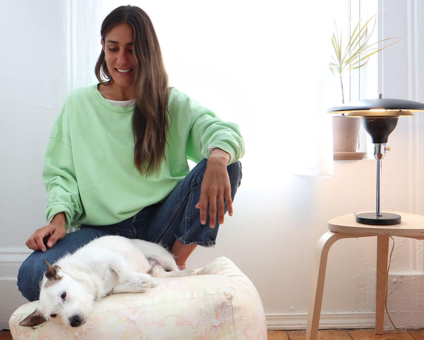 A woman sitting on a bean bag chair with a dog