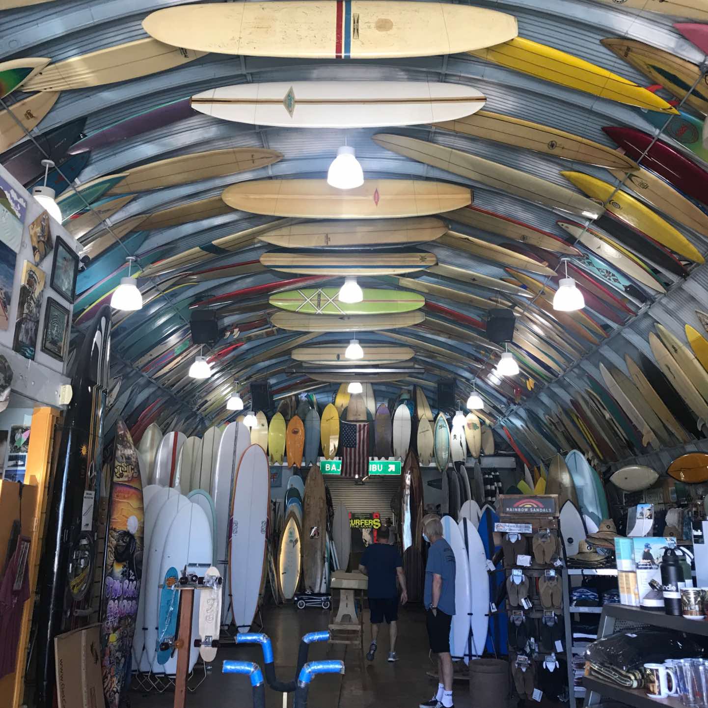 A surf shop with many surfboards hanging from the ceiling