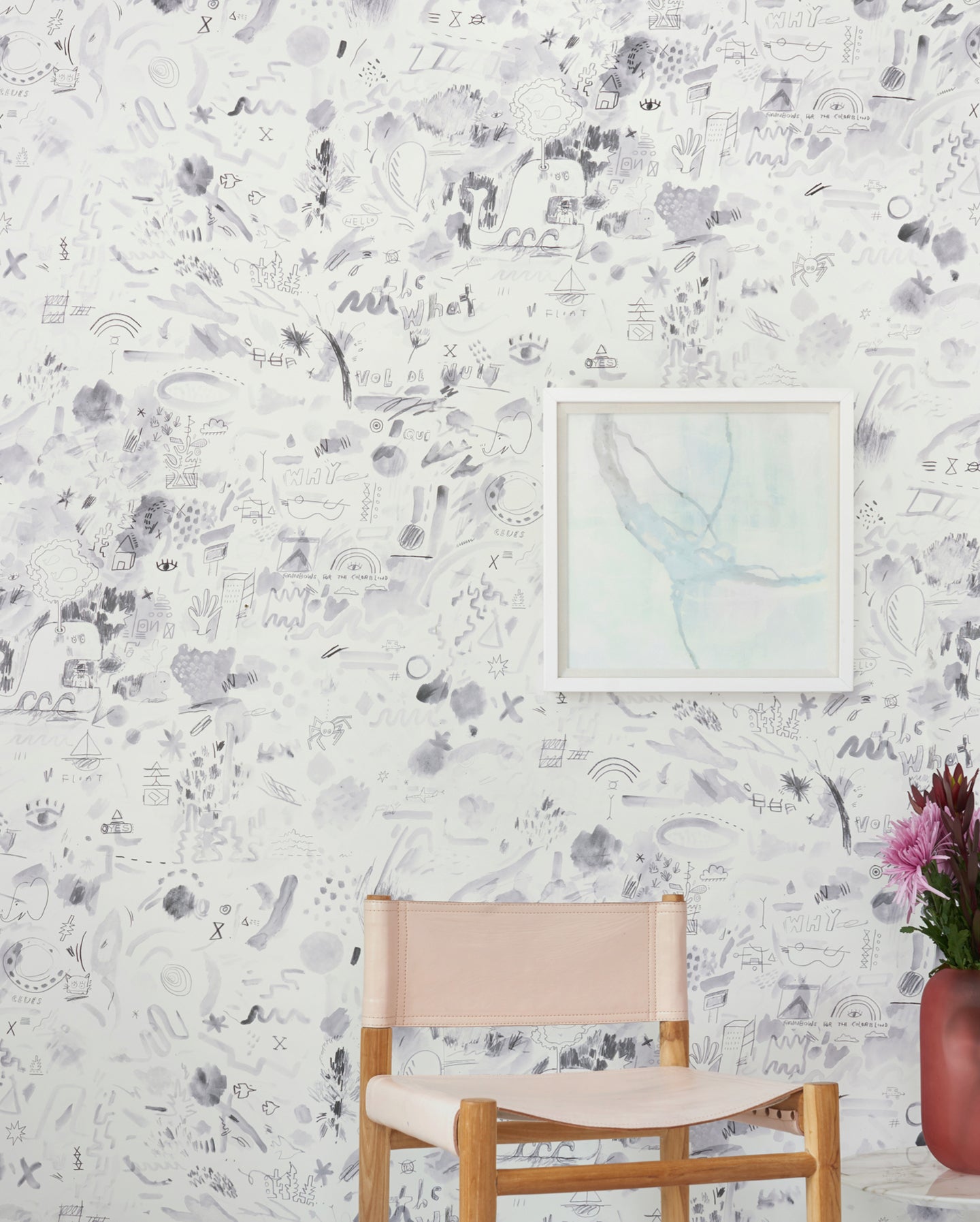 A chair with a vase in front of a white wallpaper