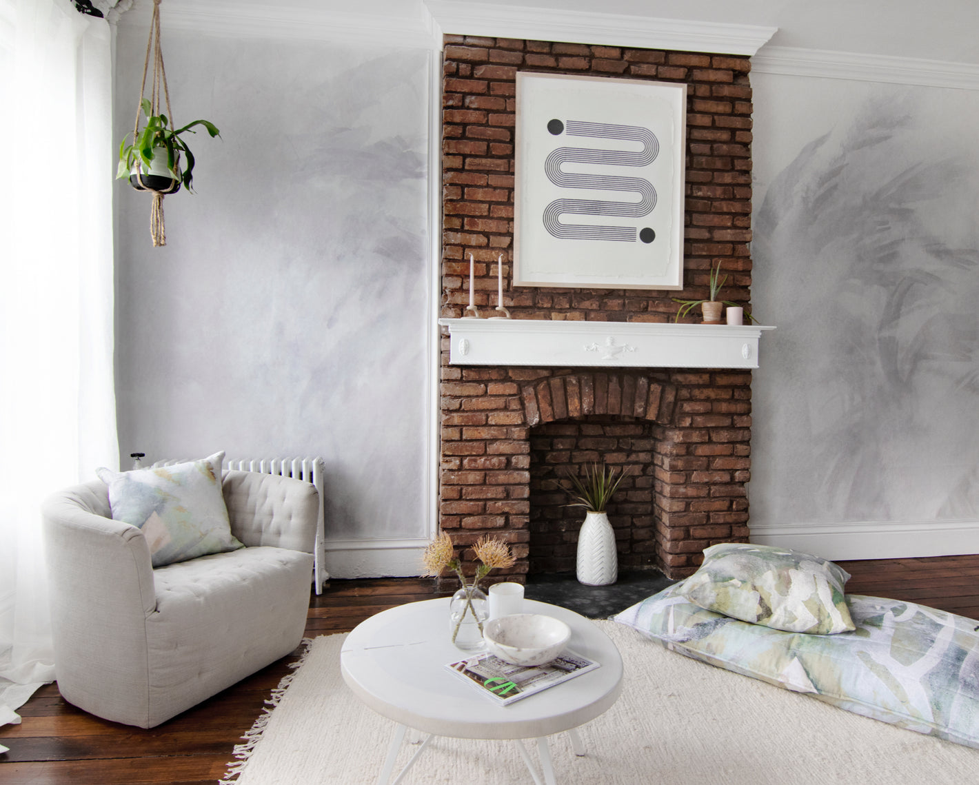 A living room with a brick fireplace and white furniture