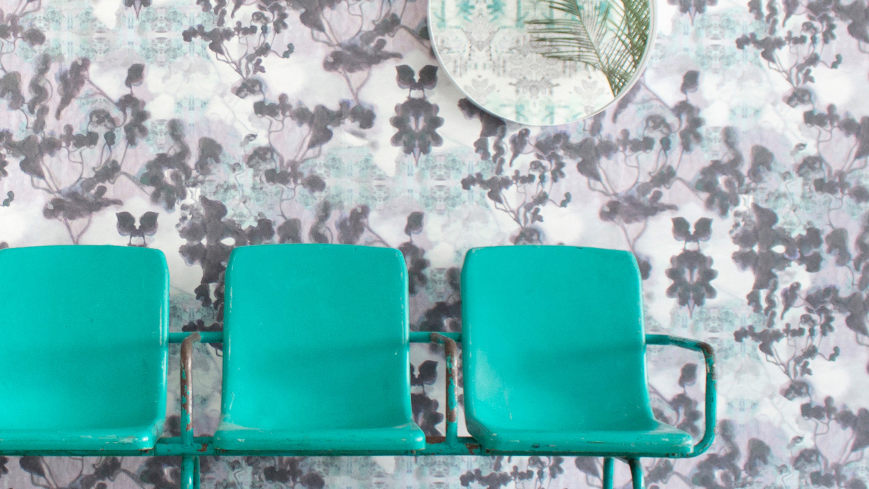A row of chairs in front of a wall with a floral pattern