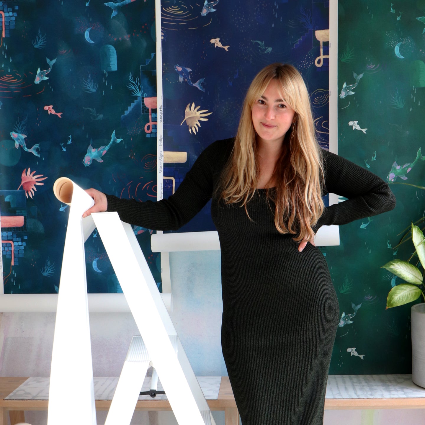 A woman standing next to a ladder in front of wallpaper