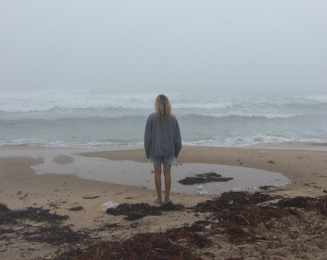 A woman standing on a beach, gazing at the vast ocean