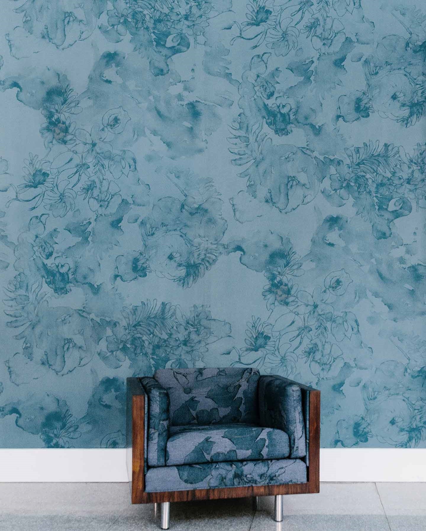 Eskayel's Belize Blooms mural in the colorway aquamarine installed as a wallpaper and used to upholster a chair. 