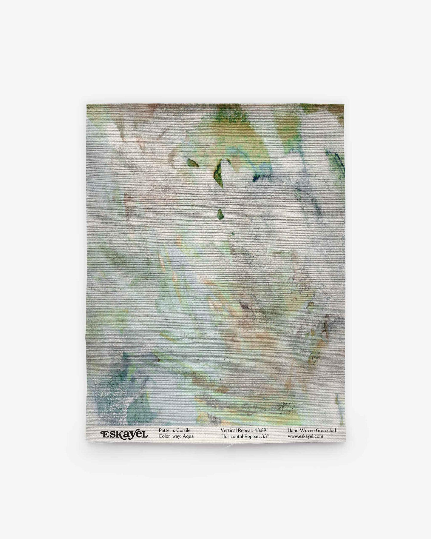 A square textile titled “Cortile Grasscloth||Aqua” features a light, abstract watercolor pattern in white, green, and blue hues that evoke the serene beauty of an Italianate garden. The label at the bottom displays the brand and product name in black text.