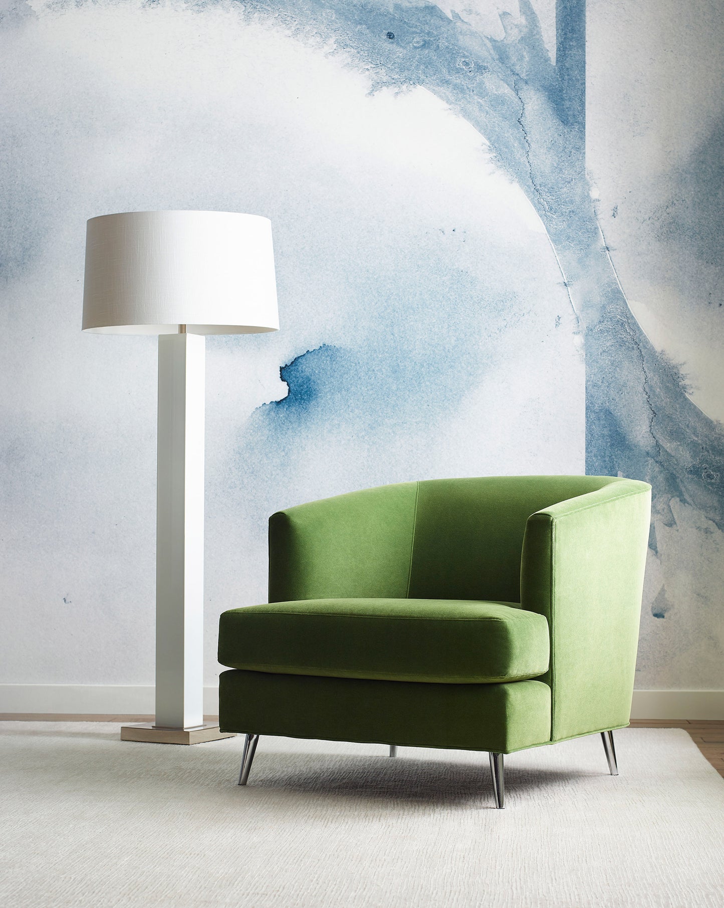 A green chair and lamp in front of a Mod Mural Wallpaper Indigo with abstract design
