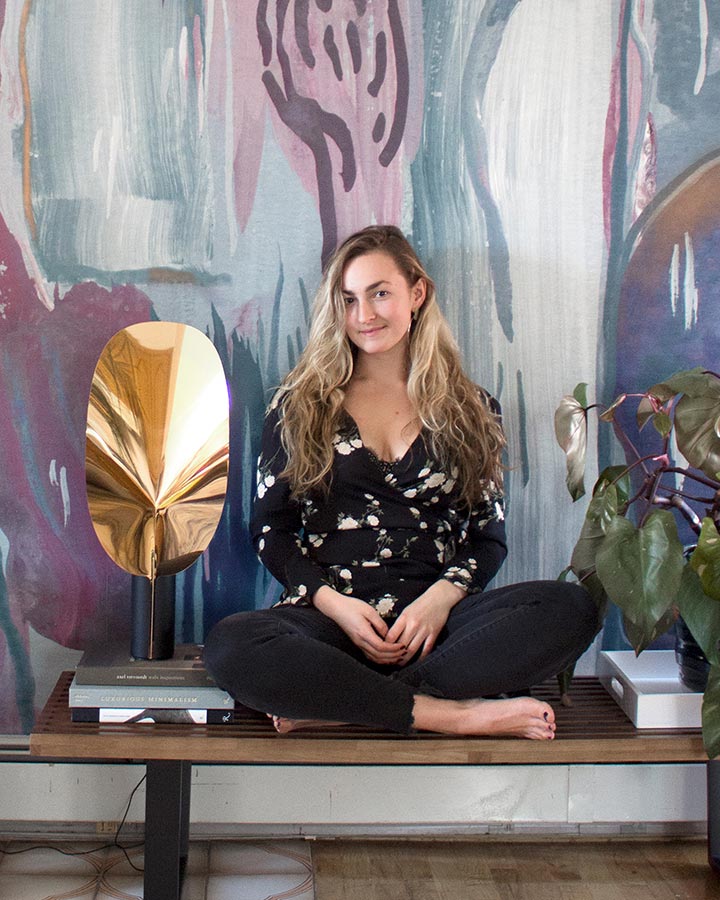 A woman sitting on a bench in front of a painting