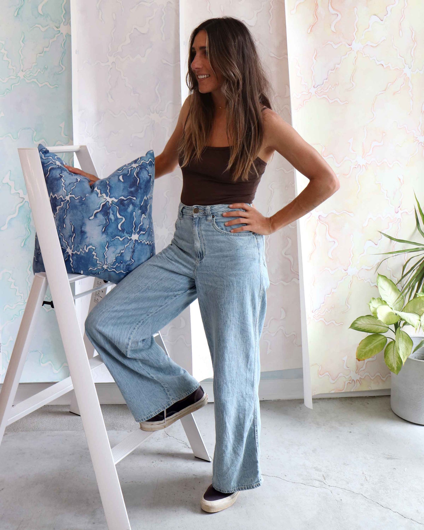 A woman is standing on a ladder with a blue pillow