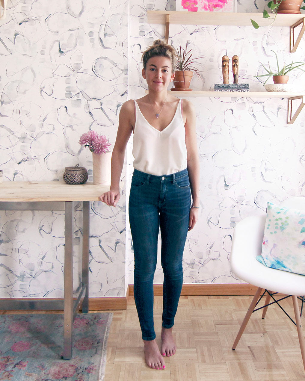 A woman standing in a room with floral wallpaper