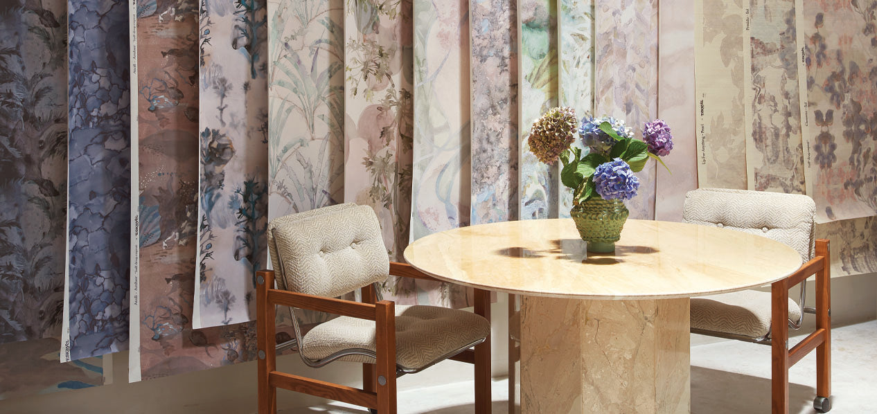 Round table with chairs in a room with wallpaper swatches on the wall.