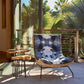 A luxurious Dynasty Performance Fabric Indigo lounge chair on a Tuscany patio surrounded by palm trees