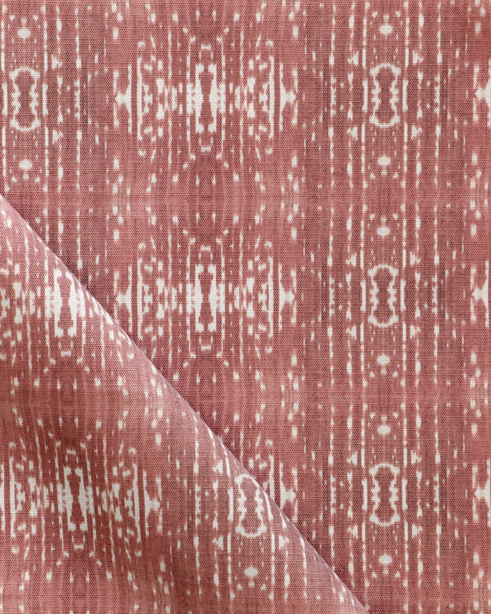 A pink and white Omaha Kinship Performance Fabric in the Morinda Ikat colorway with a geometric pattern