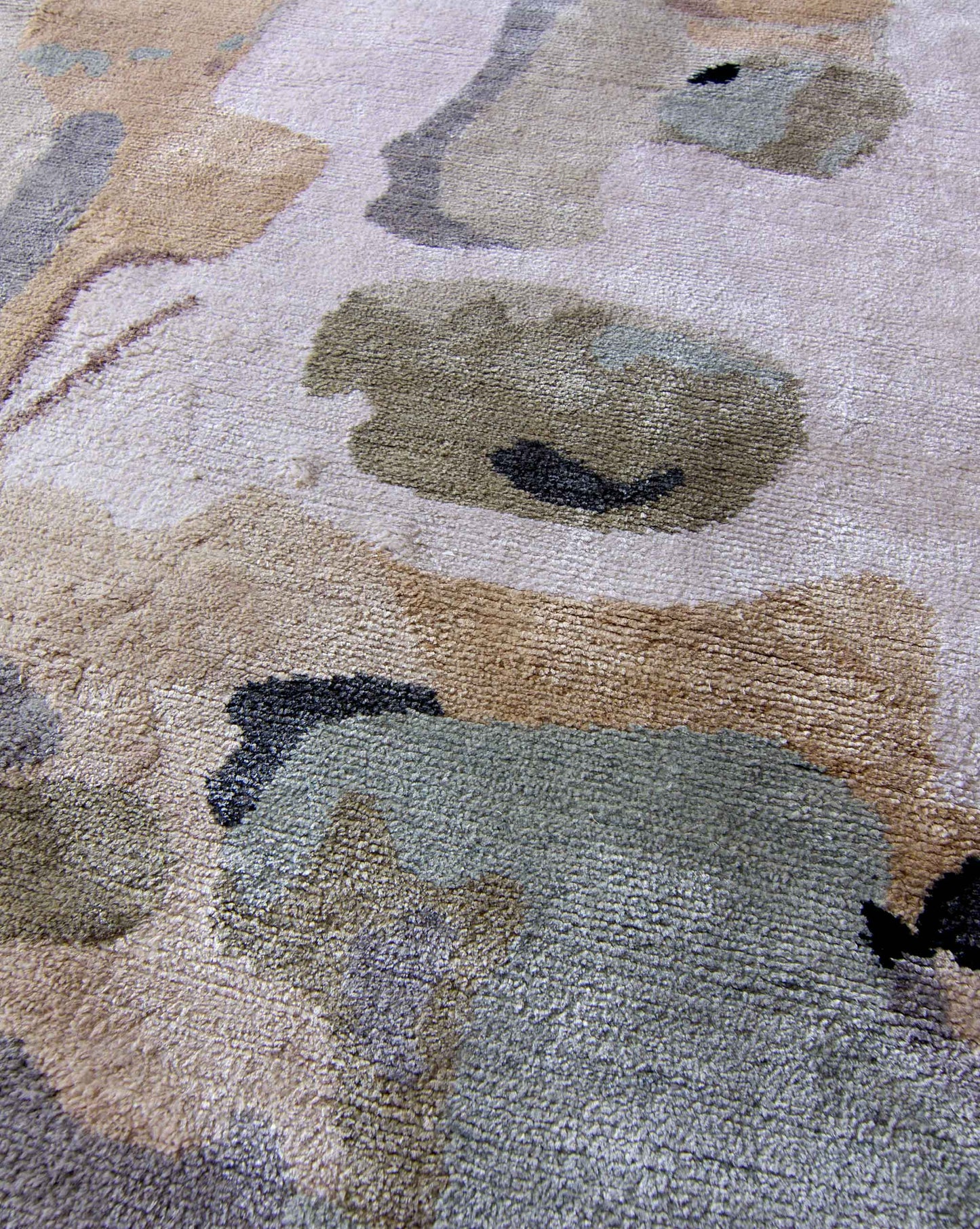 Close up image of our hand knotted Medina Blanca rug with abstract designs in a color palette of tans, greys, and black | Eskayel