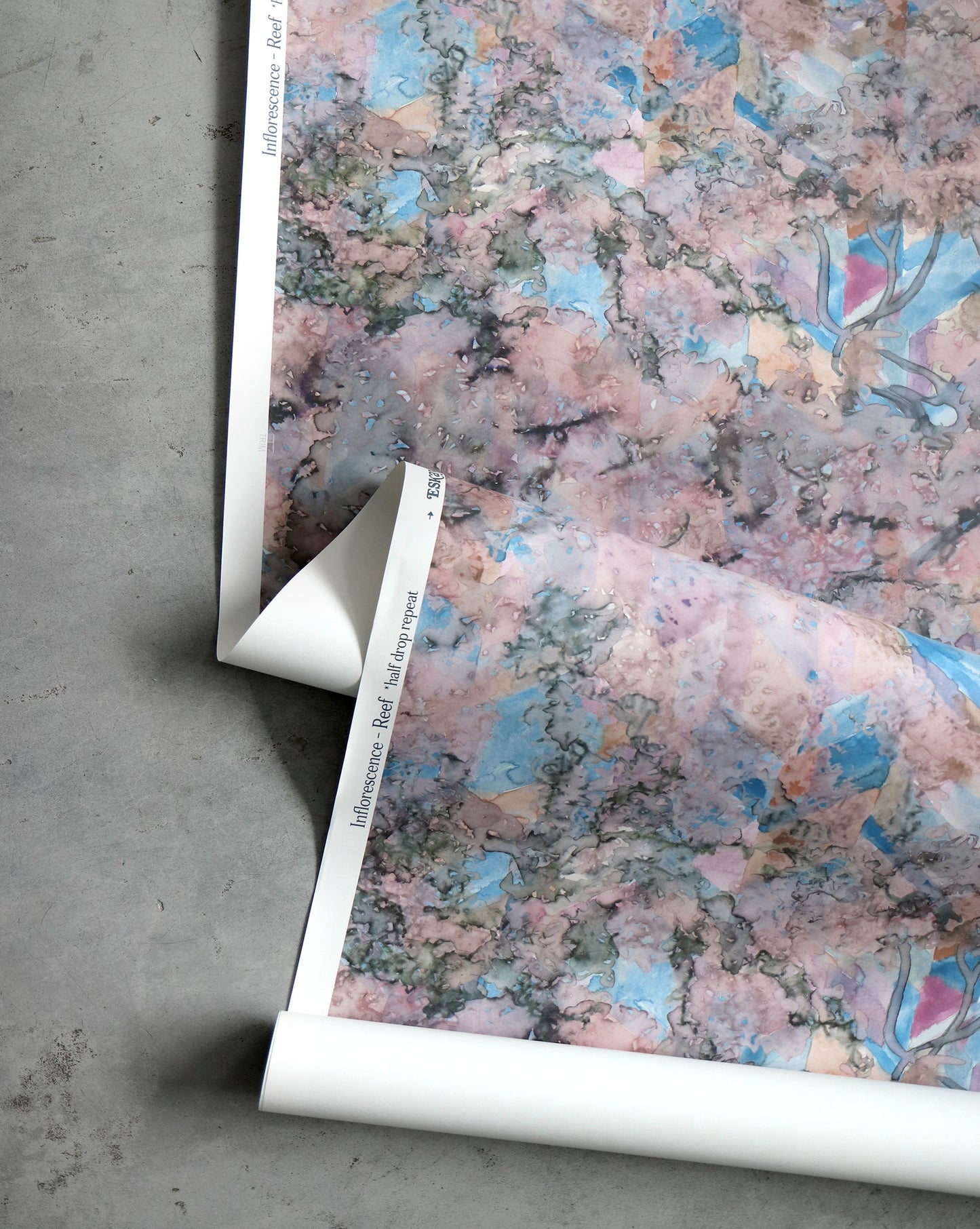 A roll of Inflorescence Wallpaper Reef, pink and blue flowers on it