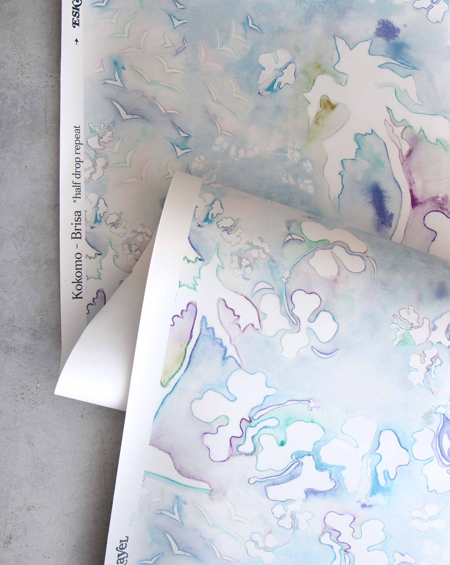 An image of Kokomo Brisa Wallpaper with blue tones and a pattern inspired by a tropical landscape of hibiscus lilies, birds, and palm trees using this idea to create one continuing line.