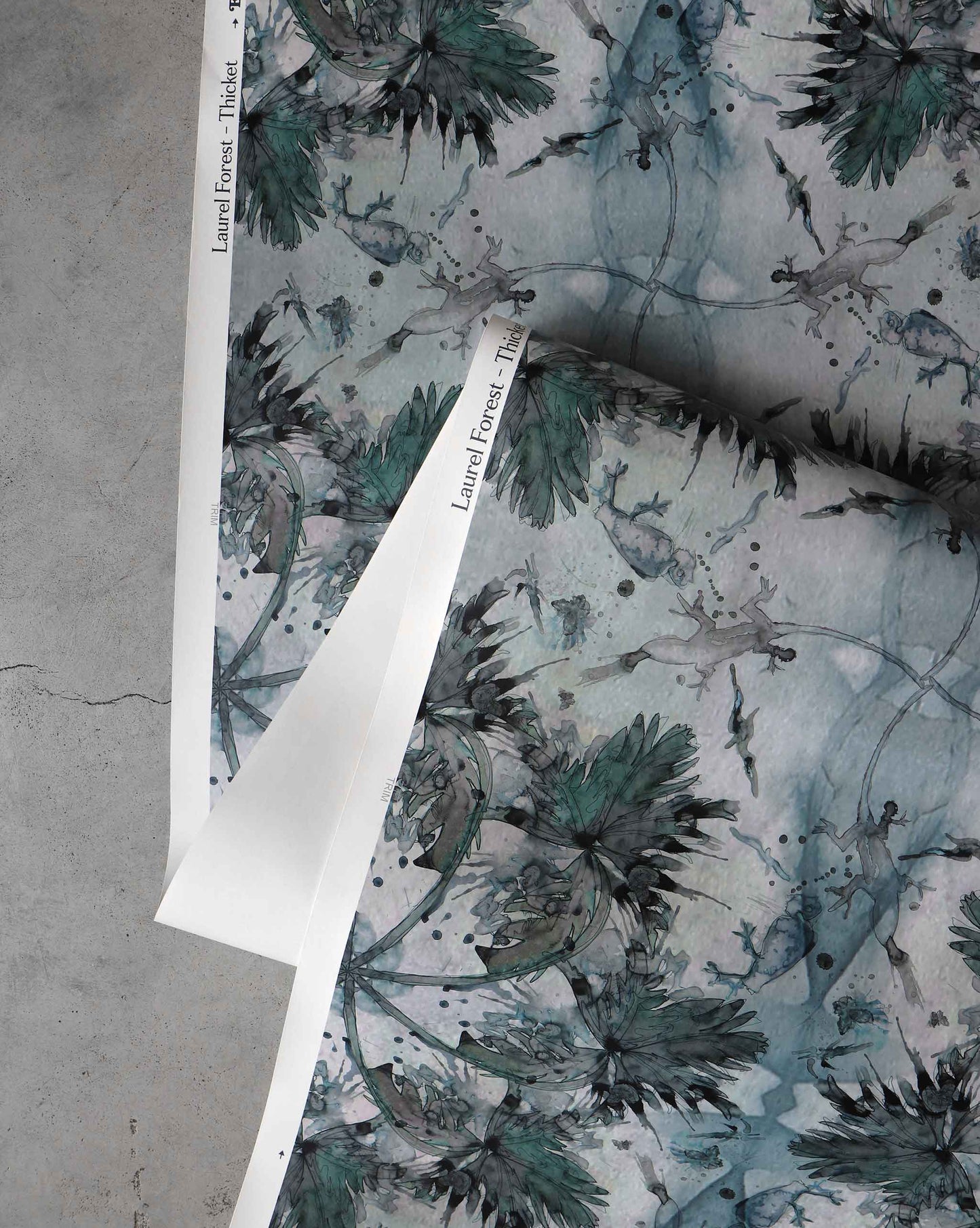 Rolled-out sheets of Laurel Forest Wallpaper||Thicket with a nature-inspired print featuring trees and foliage on a gray background, creating a tropical atmosphere.