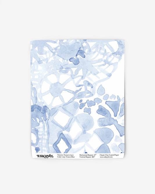 A swatch of Nonna’s Lace in Fresco Blue depicts the large-scale non-repeating wallpaper pattern in blue tones.