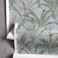 A roll of Travelers Palm wallpaper Sage with palm leaves on it