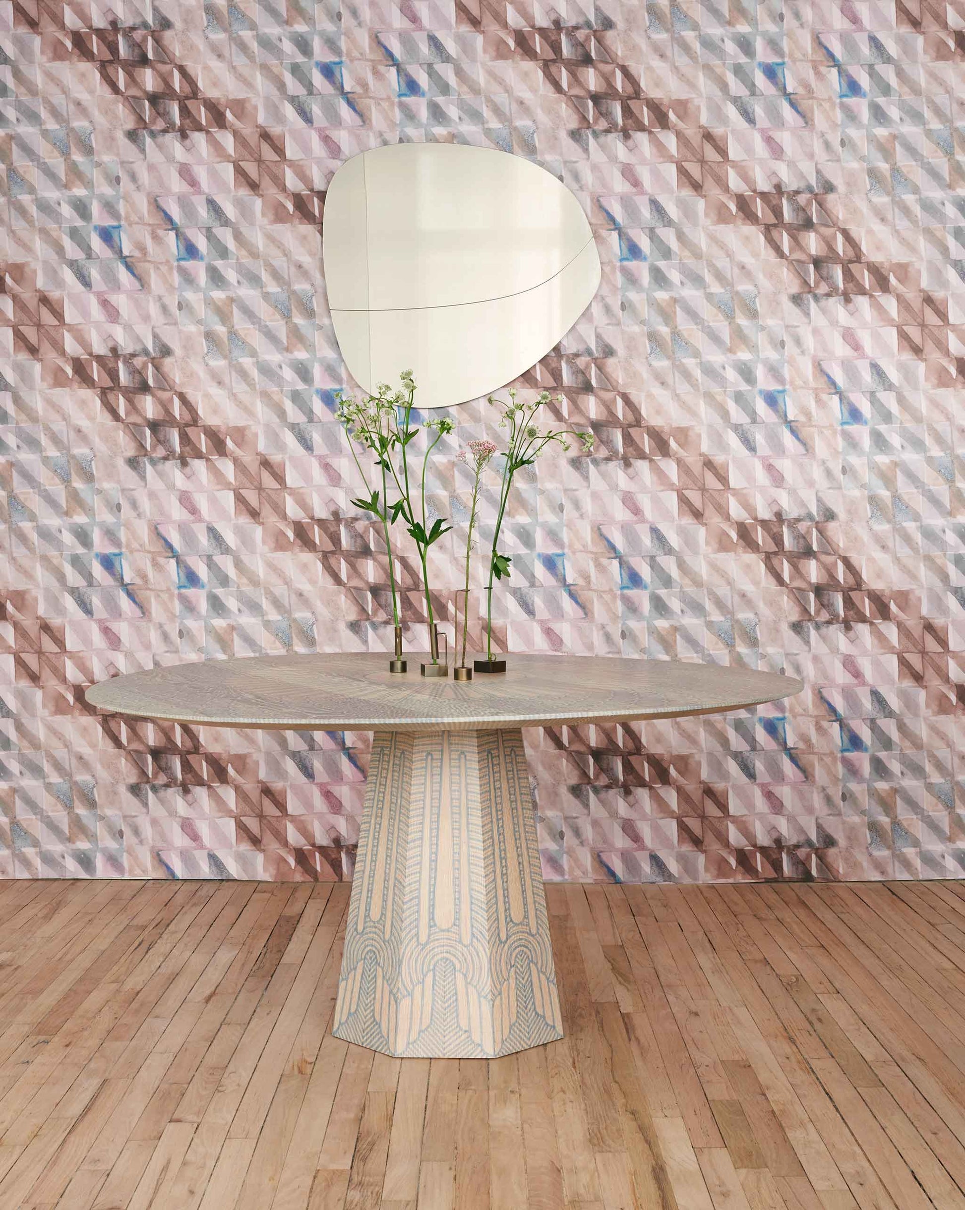 A table with a vase on it in front of a tiled wall decorated with Triangle Checks Wallpaper Camel