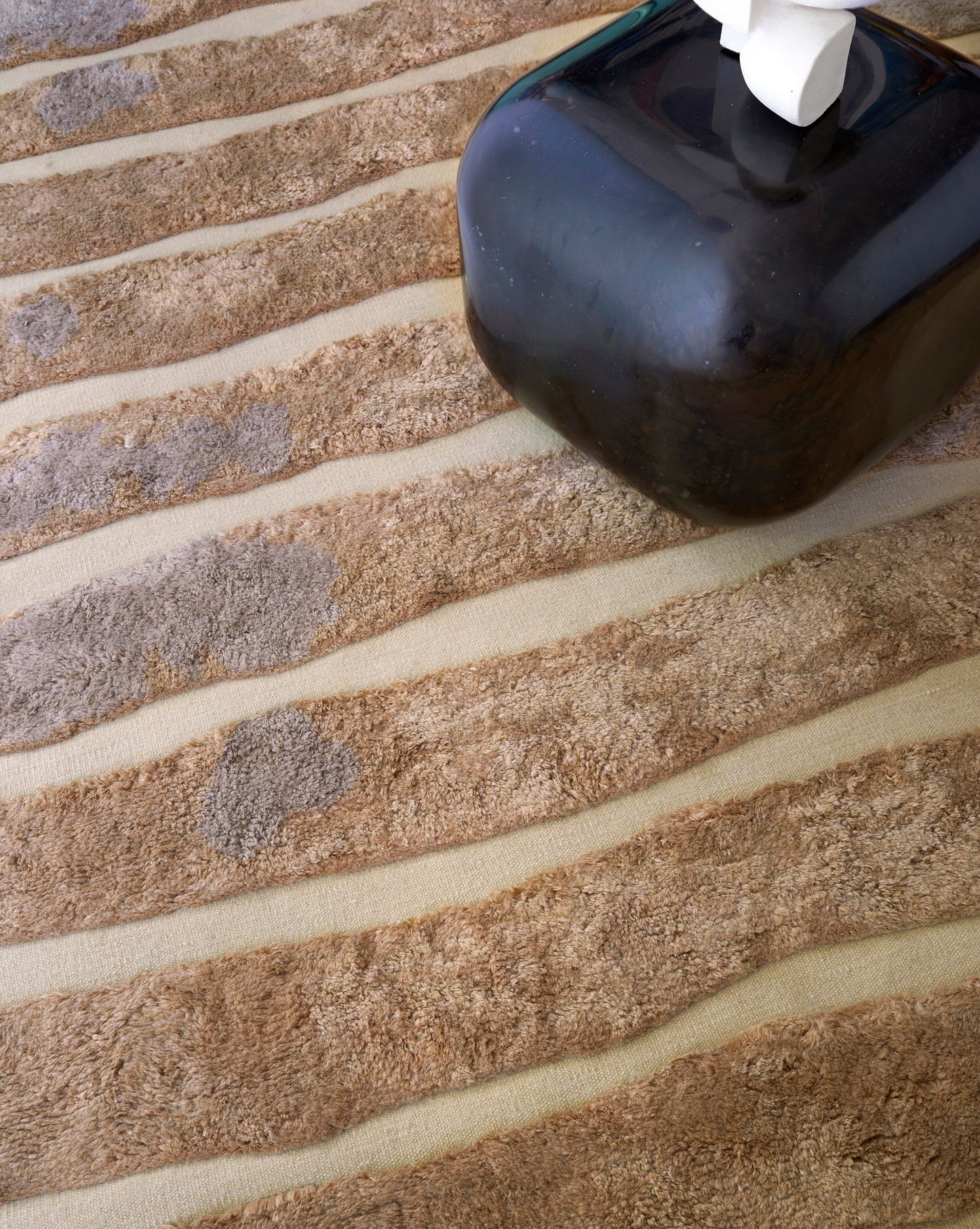 A black jug sitting on a Bold Stripe Hand Knotted Rug 6' x 9' Sienna tile floor