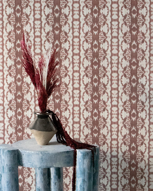 A stool with a flower on it in front of Bali Stripe Grasscloth Morinda Ikat wallcoverings