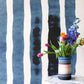 A vase of flowers on a marble table in front of a Bold Stripe Grasscloth Azure wall
