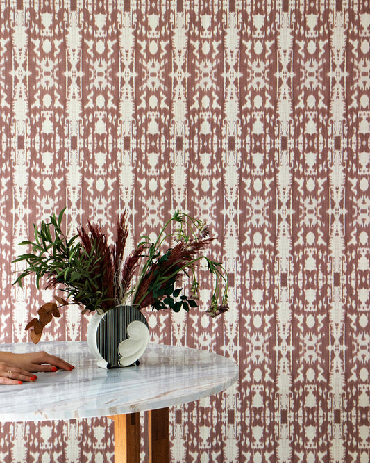 A woman is sitting at a table with a vase of flowers, surrounded by Biami Grasscloth