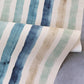 A blue and tan striped Gradient Stripe Grasscloth wallpaper adorns a table