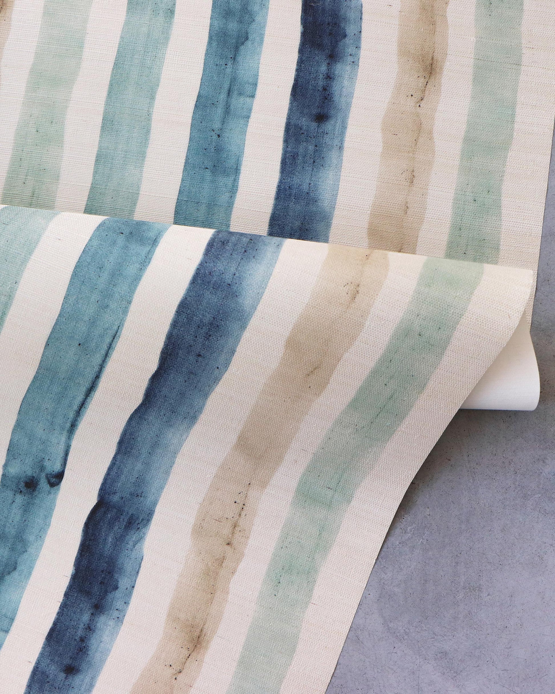 A blue and tan striped Gradient Stripe Grasscloth wallpaper adorns a table