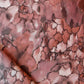 A close up of the Aquarelle Fabric in Earth colorway, showcasing nature's raw power in the pink and brown marbled pattern