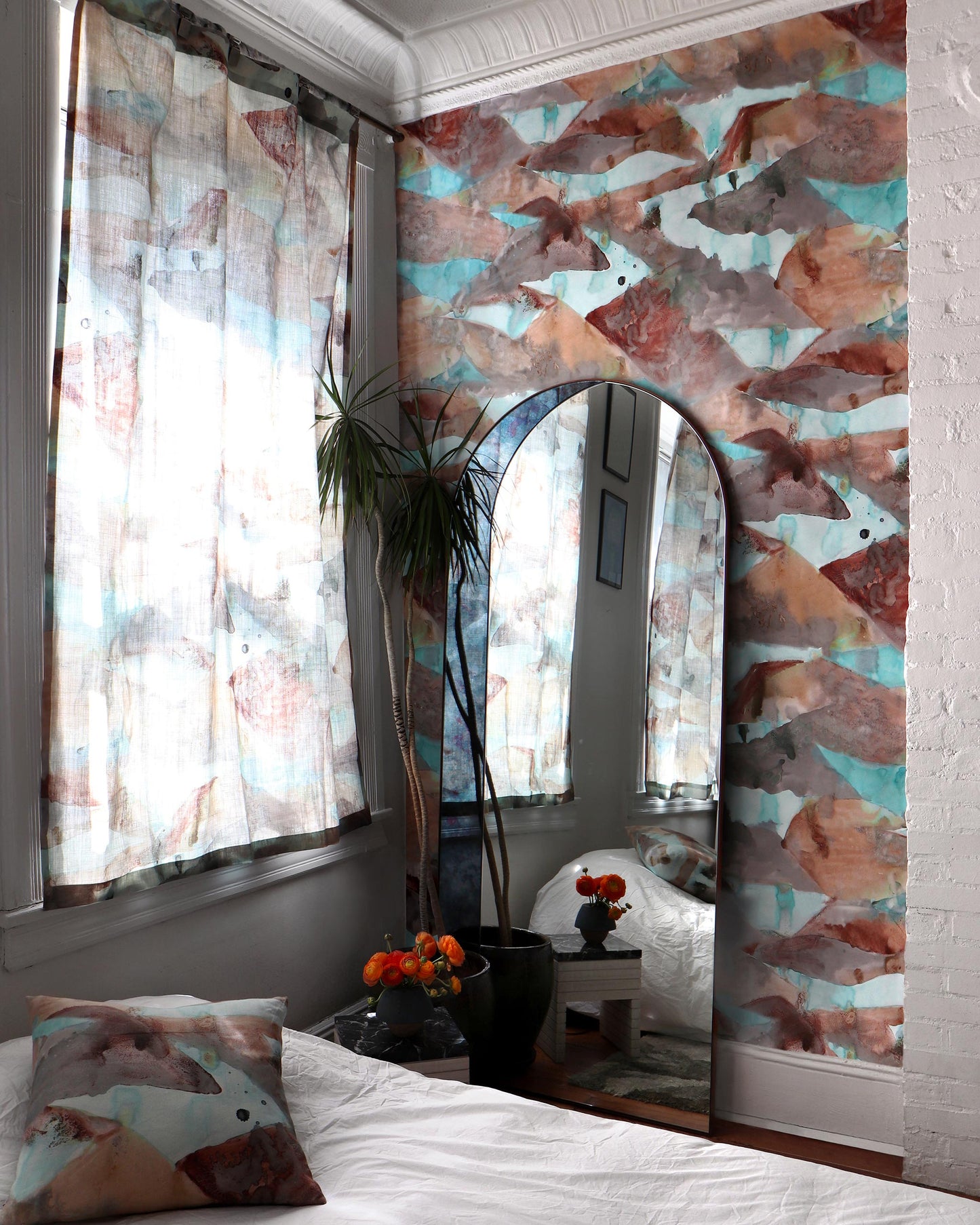 A bedroom with a bed and a mirror for Mani Fabric Morea, showcasing painting studies and vibrant colorways