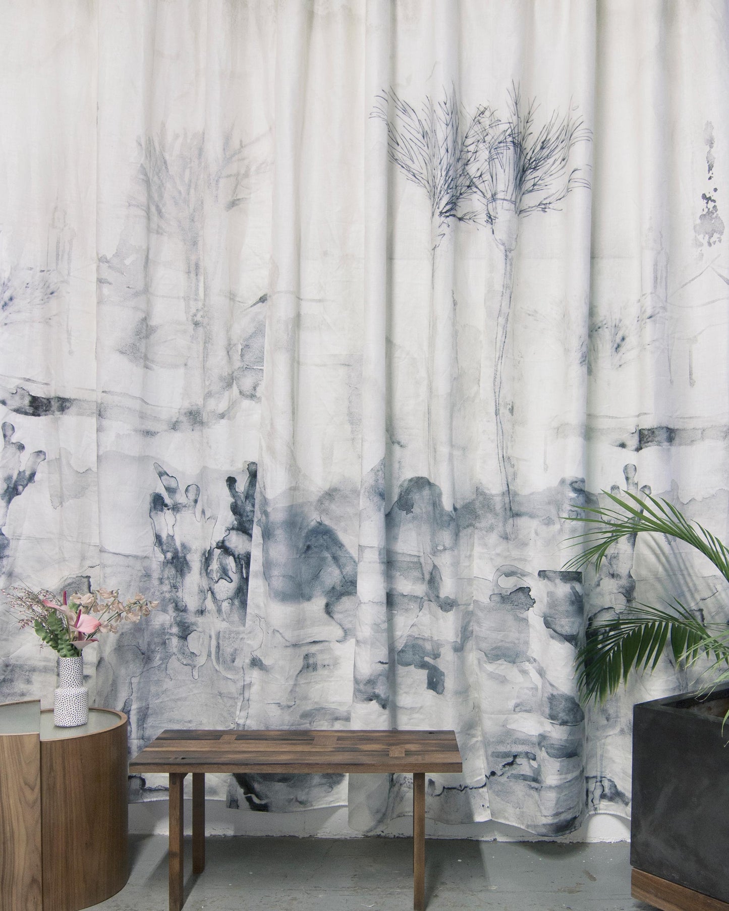 A room with Palmeraie Fabric curtains and a bench in front of it