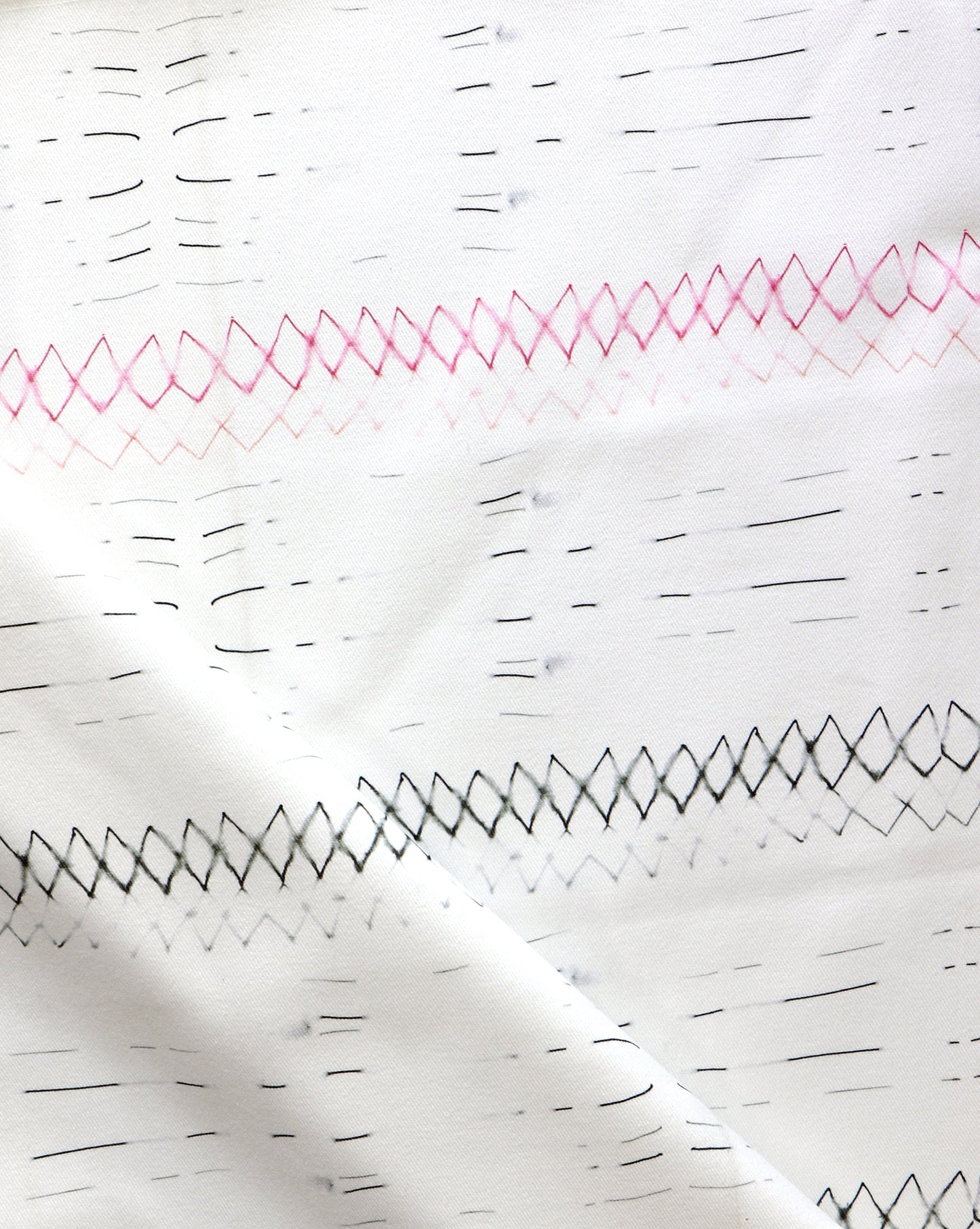 A close up of Native Stripe Fabric Black + Crimson with a graphic pattern of black and pink lines