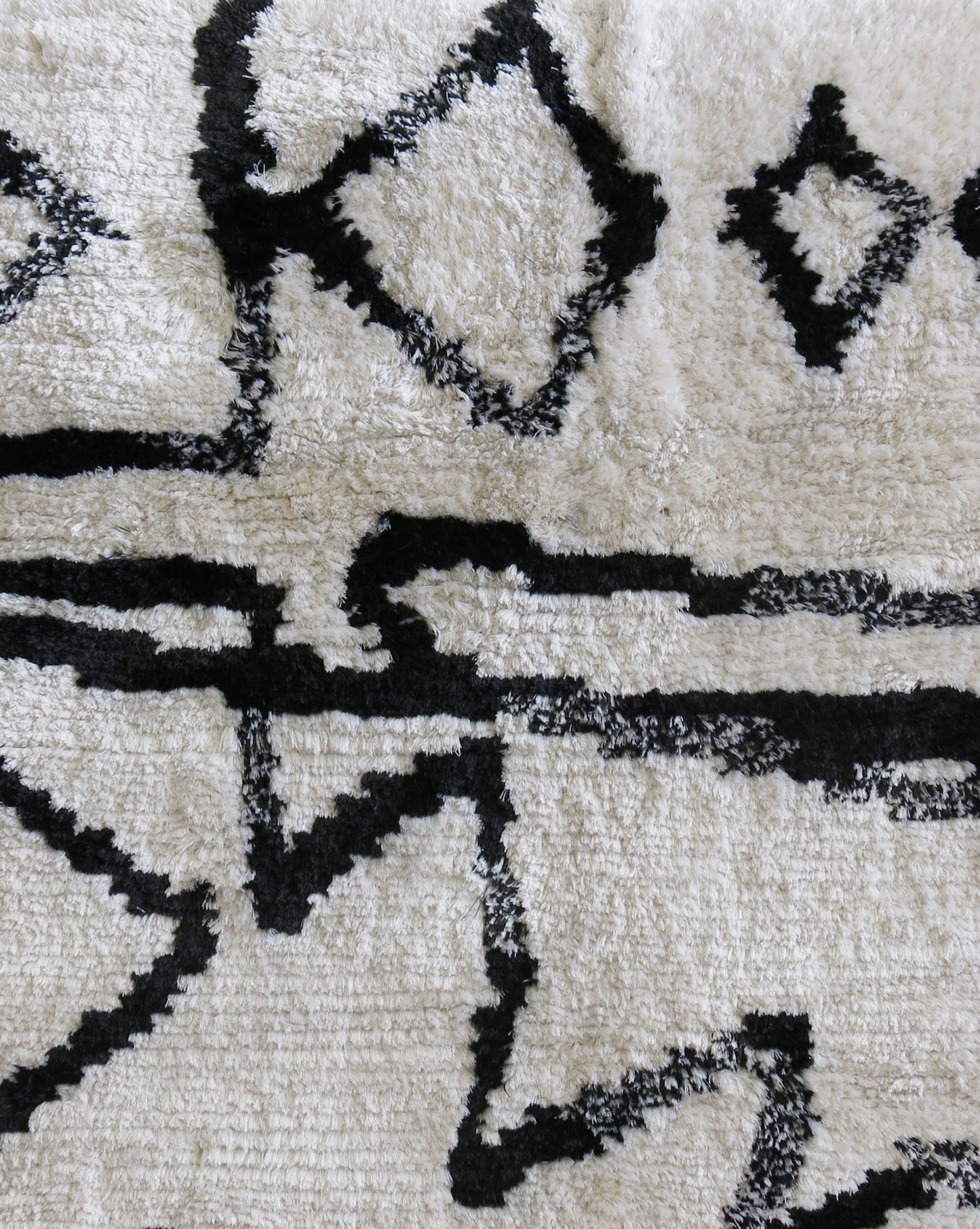 An Akimbo Hand Knotted Rug Black And White with graphic geometric designs on it