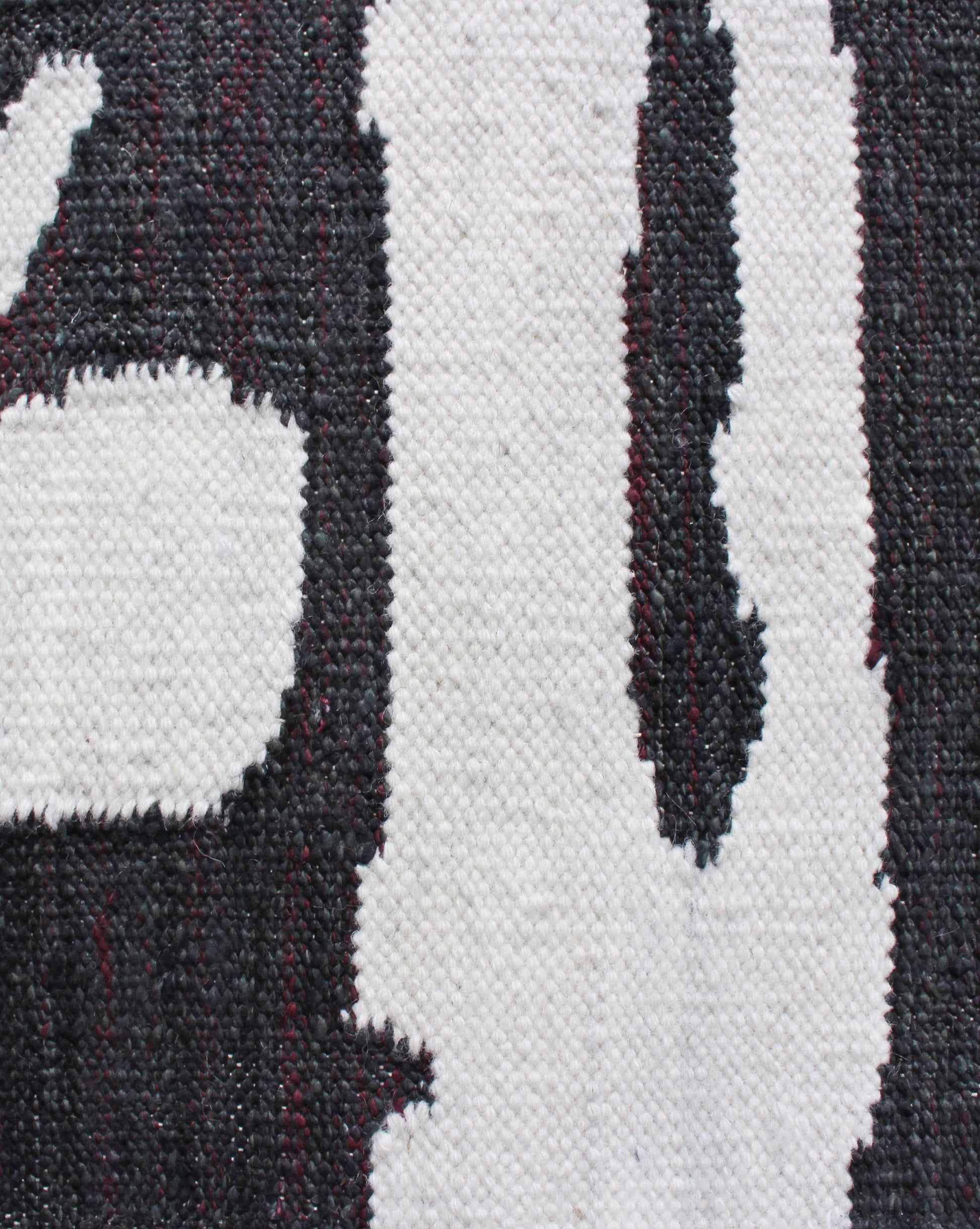 A close up of a black and white Banda Flatweave rug from Eskayel