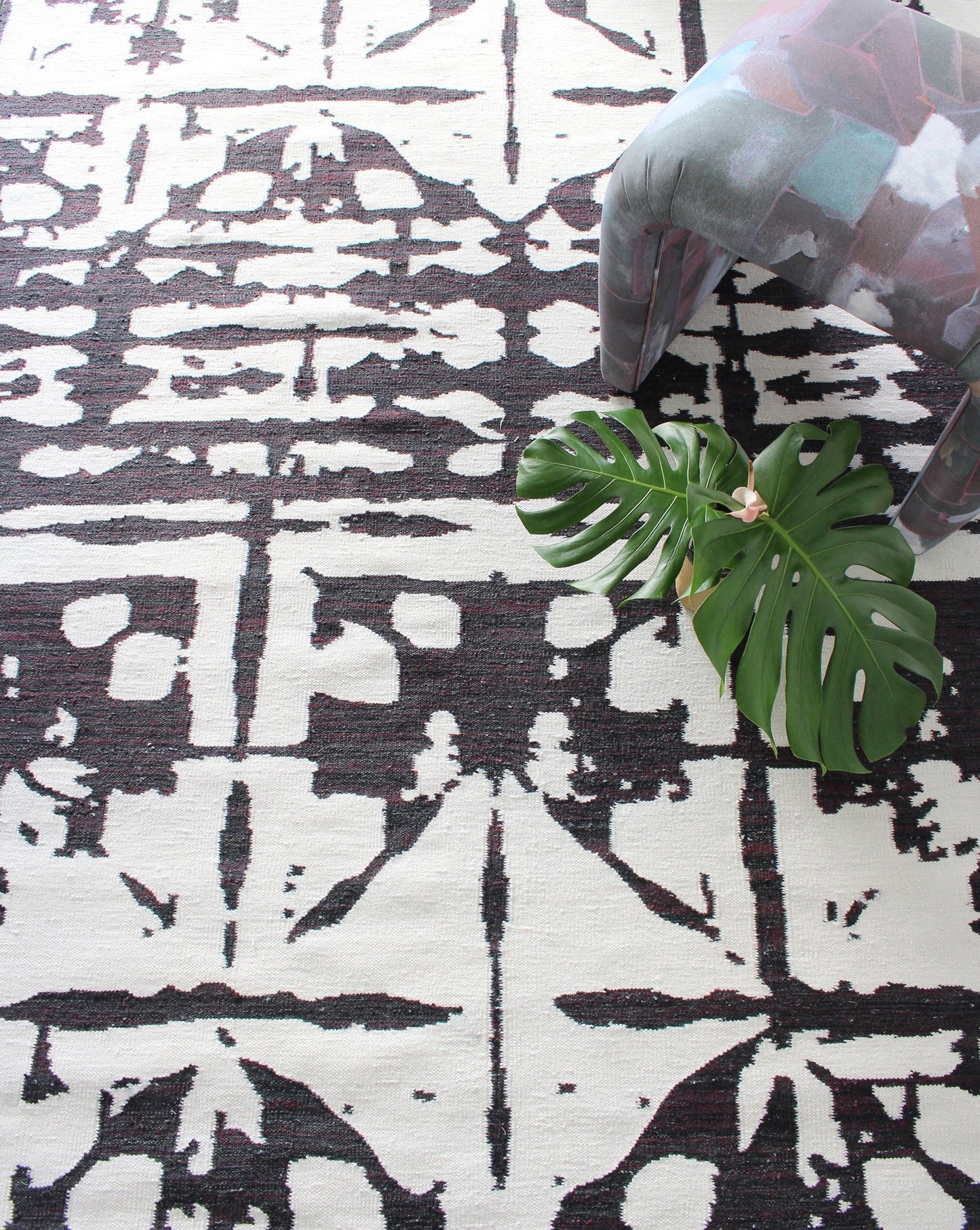A Banda Flatweave Rug Black And White with a plant on it