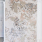 A beige and floral Belize Blooms Hand Knotted Rug in the Lumier colorway hanging in a room