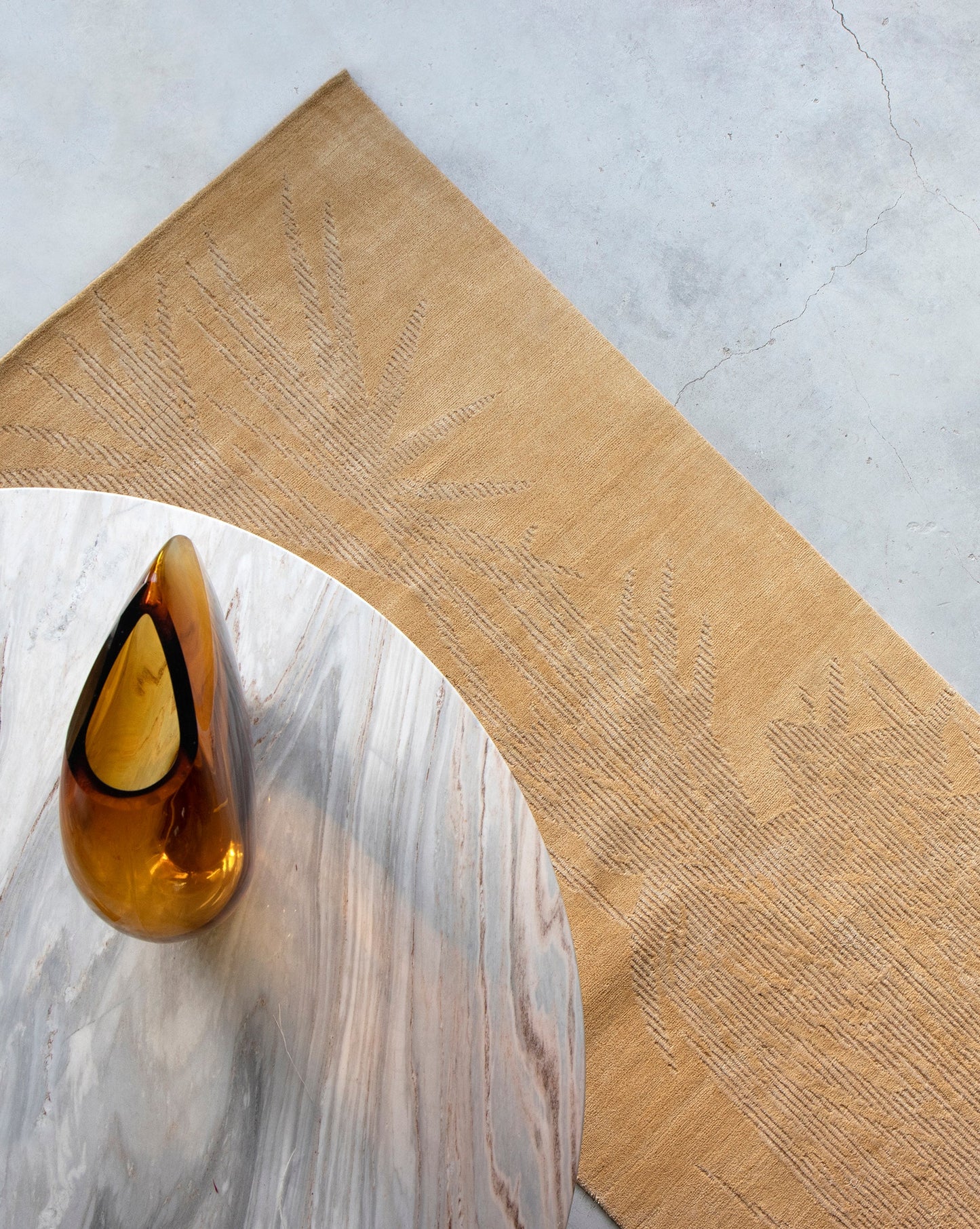A gold vase sits on a table next to a Domenica Hand Knotted Rug Gold
