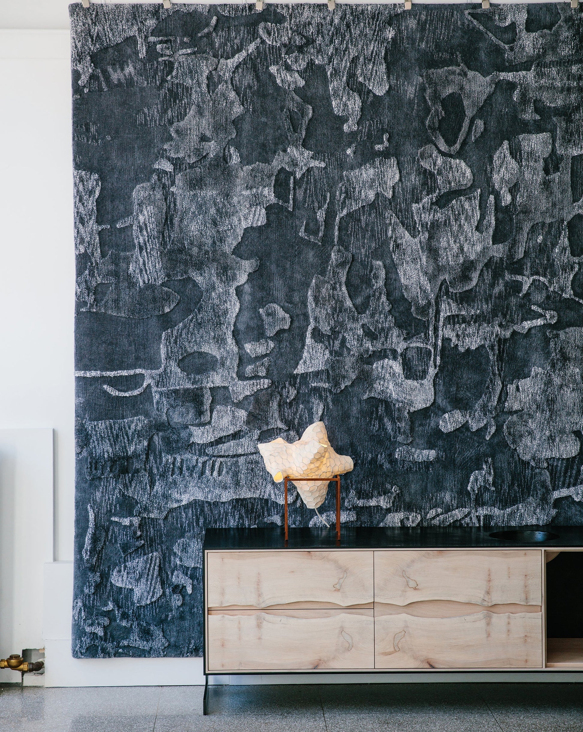 A black and white painting on a wall in a living room decorated with Kotoubia Hand Knotted Rugs