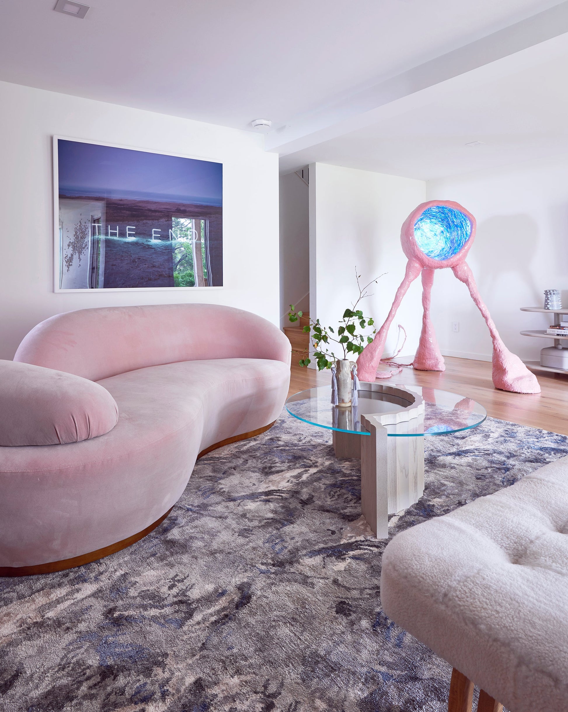 A pink couch in a living room with a Palmeti Hand Knotted Rug Notte design