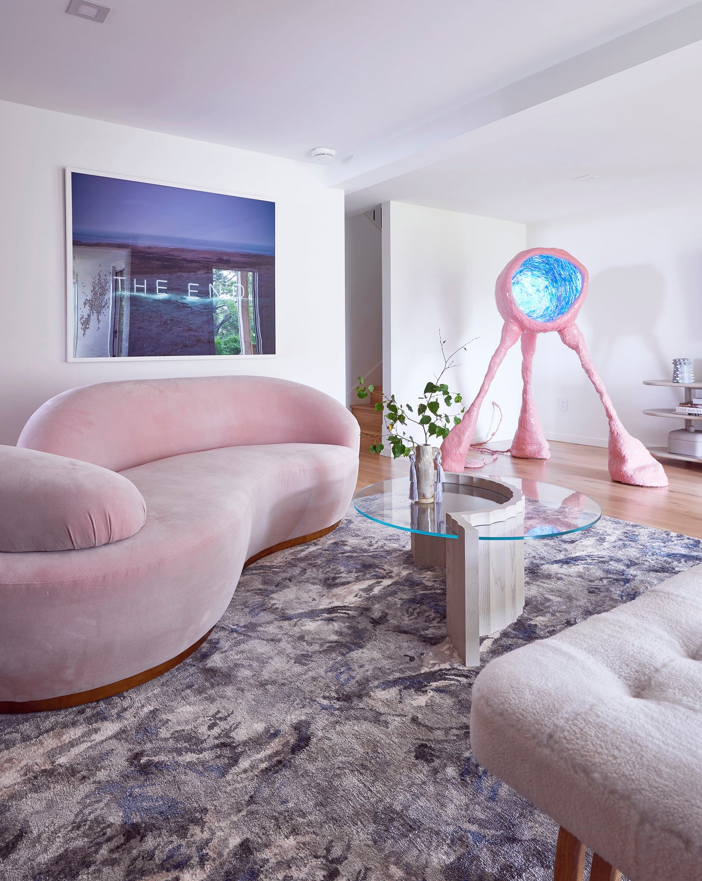 A pink couch in a living room with a Palmeti Hand Knotted Rug Notte design