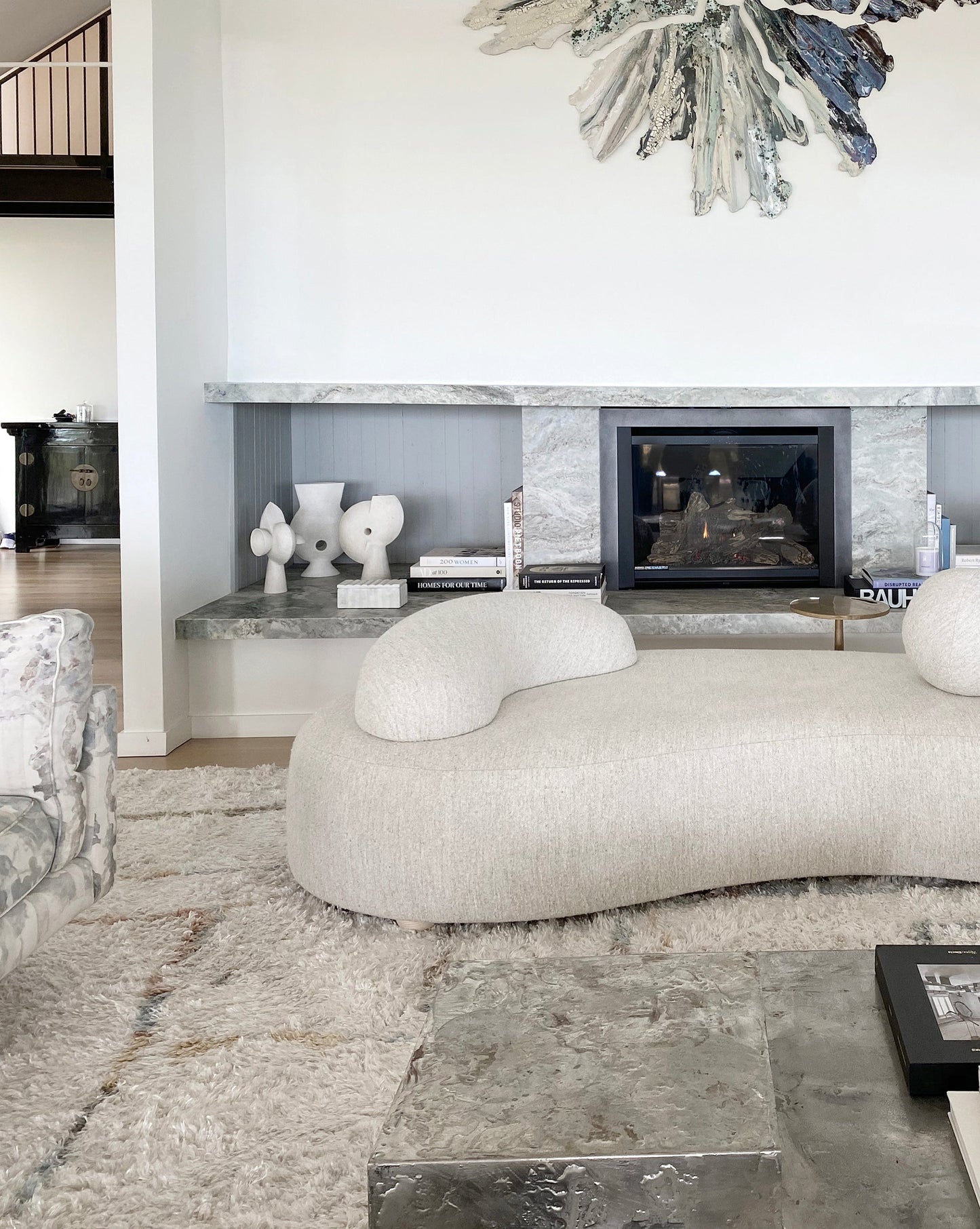 A living room with a white couch and a fireplace, featuring a Portico Hand Knotted Rug Sol