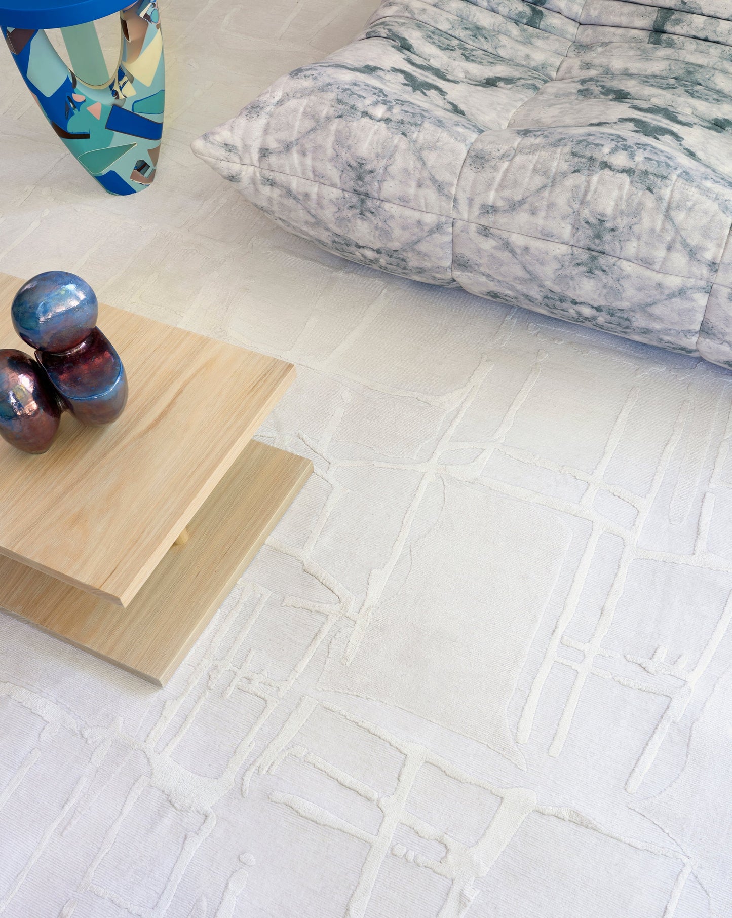A white pillow on a white floor with a Quotidiana Hand Knotted Rug Lefko White