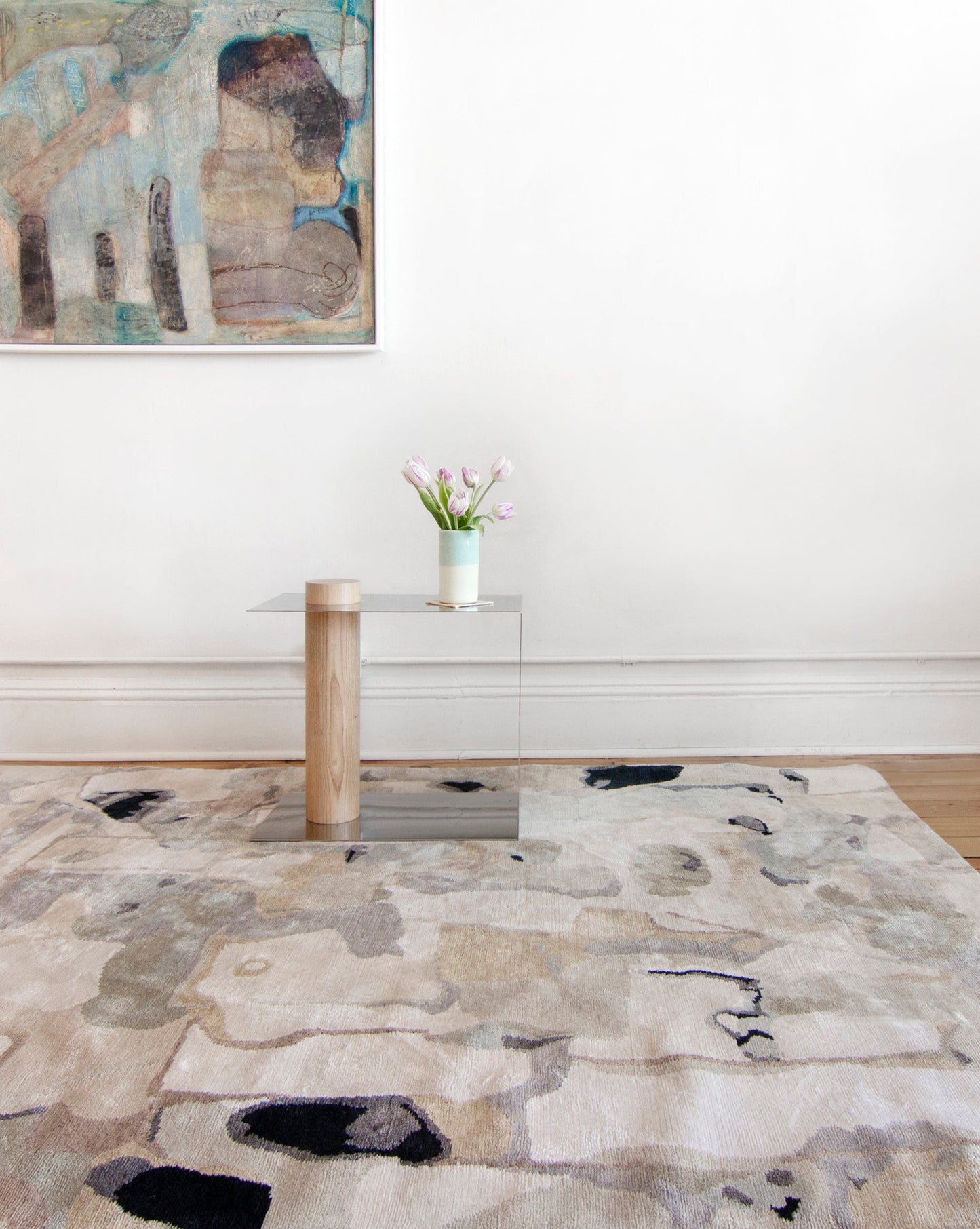 A Medina Hand Knotted Rug Blanca in a room with a painting on the wall, showcasing the influence of Medina and Marrakesh roofs