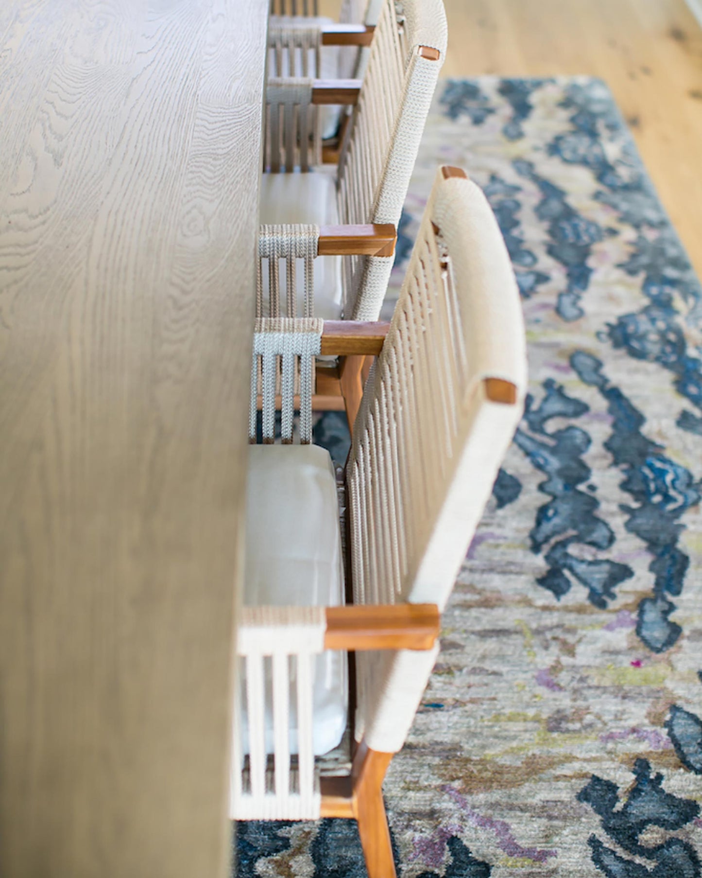 A dining table with chairs and a modern rug from The Dance Hand Knotted Rug Olive