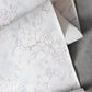 A roll of Aquarelle Wallpaper Ice with a marble pattern on it