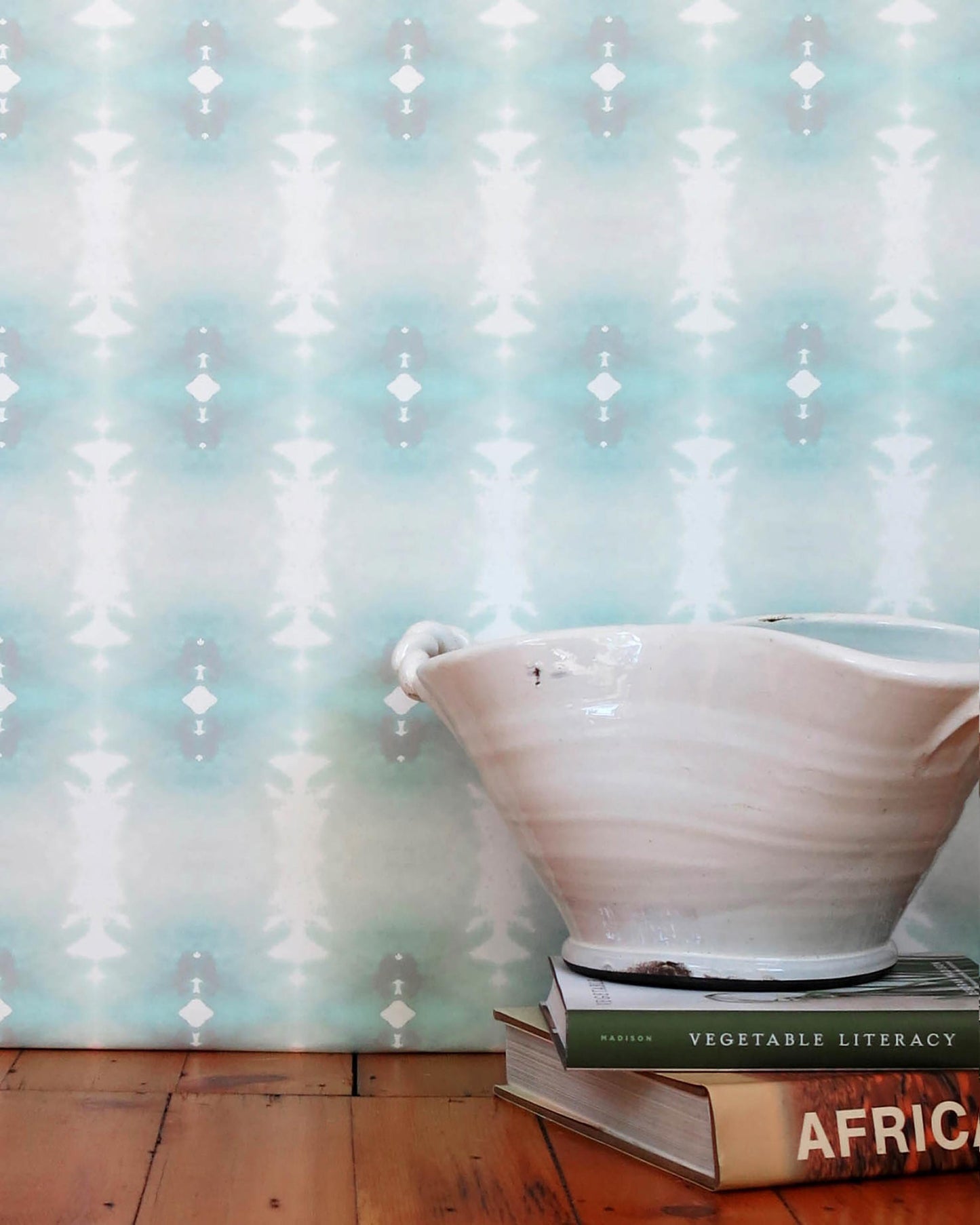 A bowl on a table next to a book, decorated with Areca Palms Wallpaper Breeze