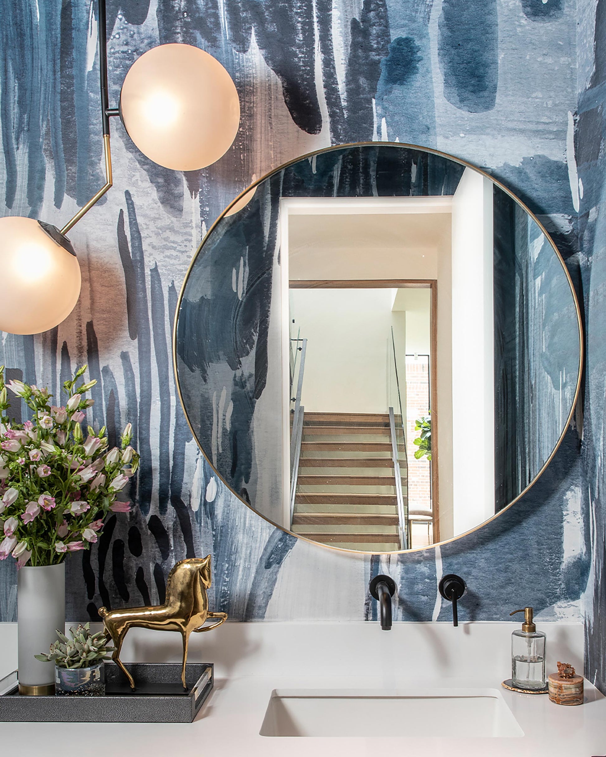 A bathroom with a round mirror and Majorelle Wallpaper Mural Cyrrus luxury fabric
