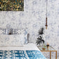 A luxury bed with a blue and white Bosky Toile Wallpaper Midnight pattern on it